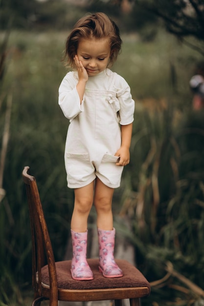 310722 Vinnitsa ウクライナ川沿いの自然の背景に曇りの天候でゴム長靴を履いた 3 歳の女の子のかわいい肖像画