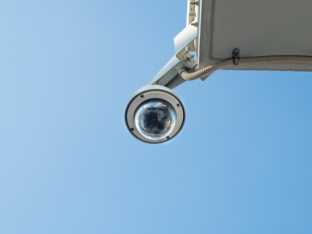 Cctv a cupola a occhio di pesce a 360 gradi installata sotto il balcone dell'edificio contro il cielo blu