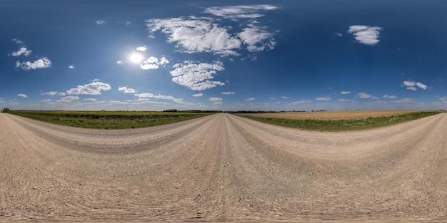 360 hdri panorama on gravel road with clouds and sun on blue sky in equirectangular spherical seamless projection use as sky replacement in drone panoramas game development as sky dome or VR content