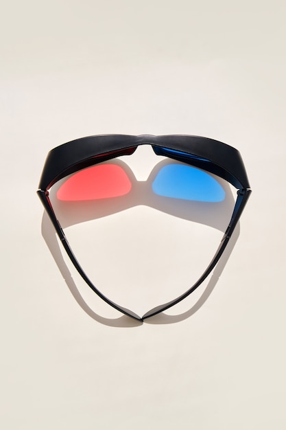 3d cinema glasses with reflex and colored shadow on beige surface