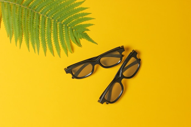 3d glasses, fern leaf on a yellow background. top view, minimalism