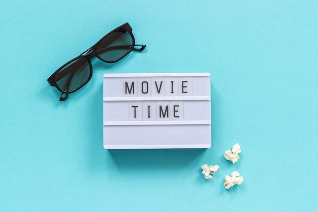 Foto testo 3d occhiali, popcorn e lightbox tempo di film su sfondo blu carta.