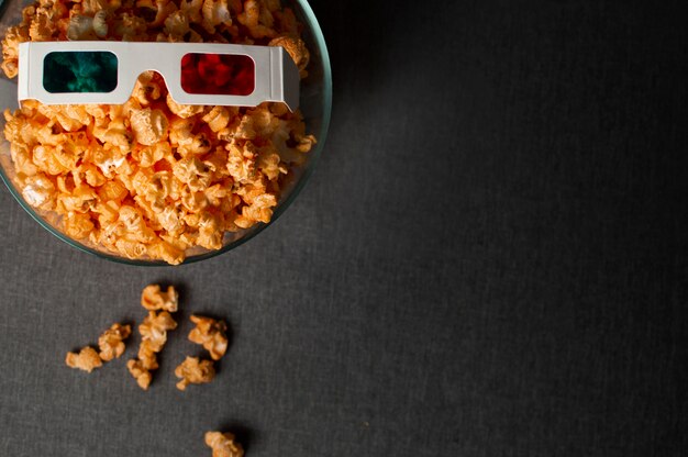 3D glasses and popcorn standing on a dark bed