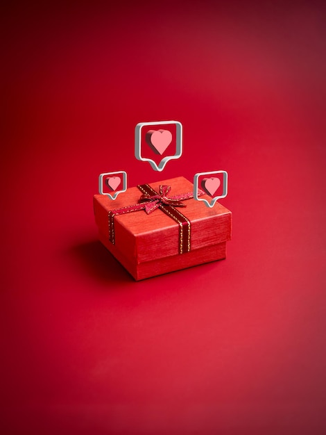 3d liefde zoals hartpictogrammen die op kleine rode huidige giftdoos met lint op rode verticale stijl als achtergrond drijven Essentieel geschenk op speciale dagen verjaardagen Nieuwjaarsdag Valentijnsdag en jubilea