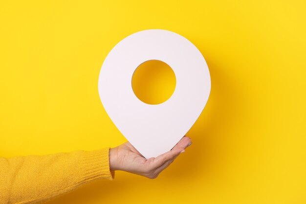 3D location symbol in hand over yellow background