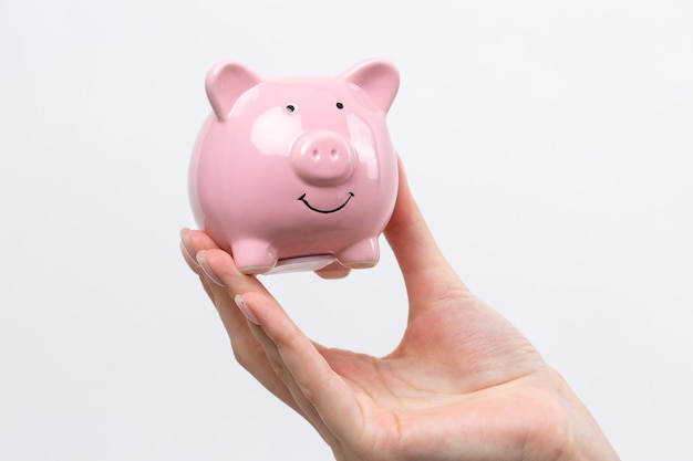 3d pink piggy bank in the beautiful hands of a girlxACloseup photo on a white background