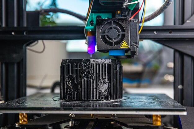 Photo a 3d printer prints a black model technology at home