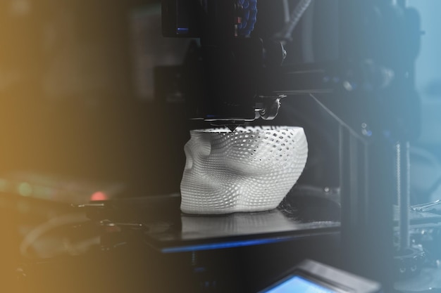 3D-принтер печатает белую пластиковую модель
