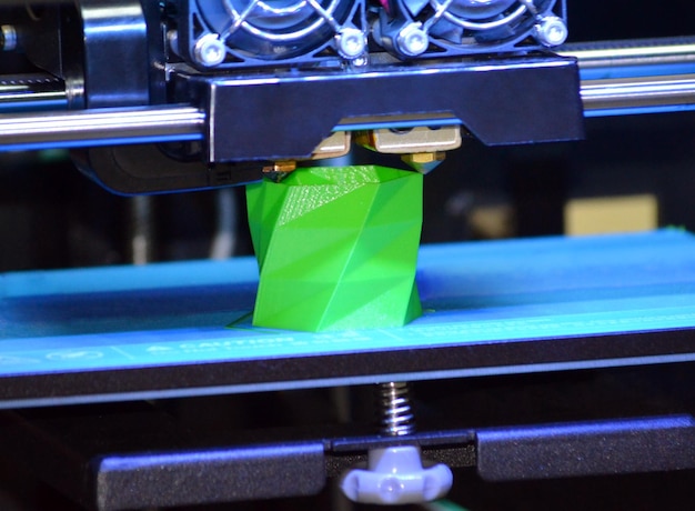 3D printer works and creates an object from the hot molten plastic