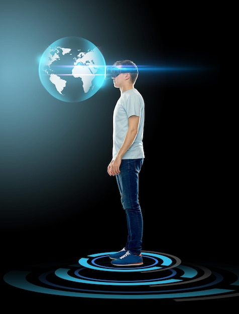 3D-technologie, gaming, augmented reality, cyberspace en mensenconcept - gelukkige jonge man met virtual reality-headset of 3D-bril kijkend naar earth globe hologram op zwarte achtergrond