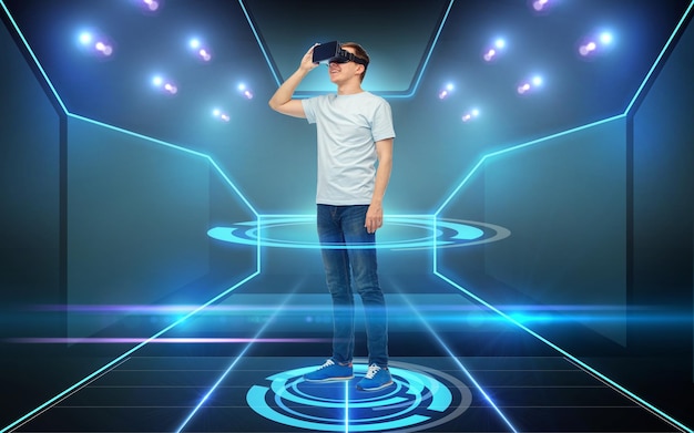 3D-technologie, virtual reality, cyberspace en mensenconcept - gelukkige jonge man met virtual reality-headset of 3D-bril op zwarte achtergrond en laserlicht