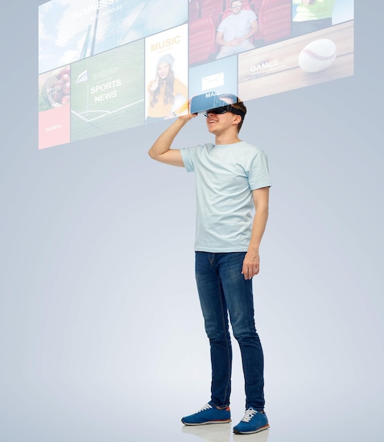 Foto 3d-technologie, virtual reality, entertainment, cyberspace en mensenconcept - gelukkige jonge man met virtual reality-headset of 3d-bril kijkend naar scherm met internetnieuws