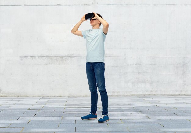 3D-technologie, virtual reality, entertainment, cyberspace en mensenconcept - gelukkige jonge man met virtual reality-headset of 3D-bril op straatachtergrond