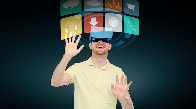 3d technology, virtual reality, cyberspace, entertainment and people concept - happy young man with virtual reality headset or 3d glasses and computer menu icons over black background