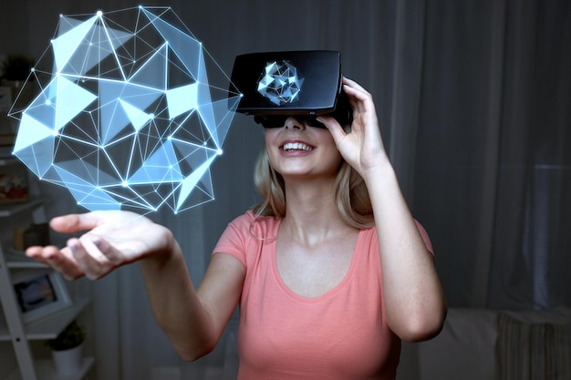 Фото 3d-технологии, виртуальная реальность, развлечения и концепция людей - счастливая молодая женщина с гарнитурой виртуальной реальности или 3d-очками, играющая с низкополигональной проекцией формы на черном фоне