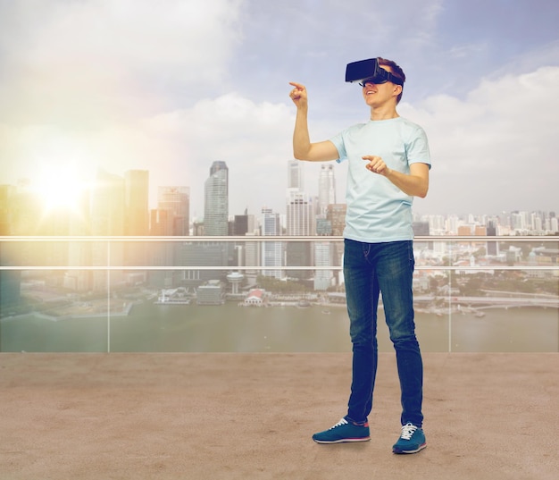 3d technology, virtual reality, entertainment, cyberspace and people concept - man with virtual reality headset or 3d glasses playing game and touching something over city skyscrapers background