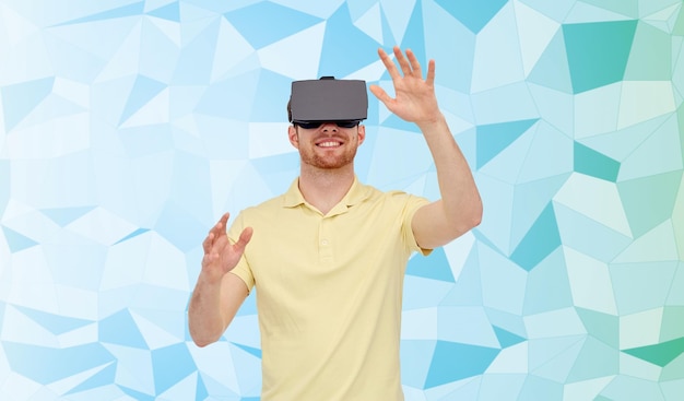 3d-технологии, виртуальная реальность, развлечения и концепция людей - счастливый молодой человек с гарнитурой виртуальной реальности или 3d-очками, играющий в игру на низкополигональном фоне