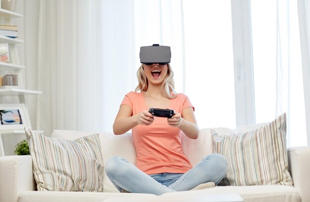 3d technology, virtual reality, gaming, entertainment and people concept - happy young woman with virtual reality headset or 3d glasses playing video game with controller gamepad at home