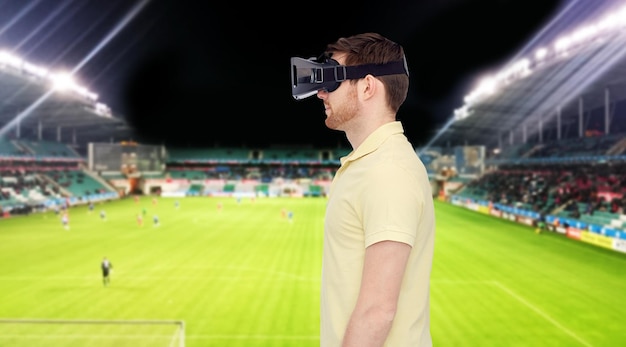 Foto tecnologia 3d, realtà virtuale, sport, intrattenimento e concetto di persone - giovane con cuffie per realtà virtuale o occhiali 3d sul campo di calcio sullo sfondo dello stadio