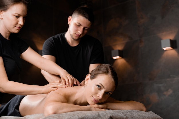 4 handen massage in de spa. Twee masseurs maken vier handen ontspannende massage met olie voor meisje. Ontspanning. Manuele therapie.