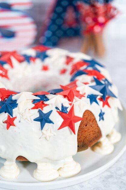 4 juli bundtcake bedekt met een vanilleglazuur en versierd met chocoladesterren op een wit bord.