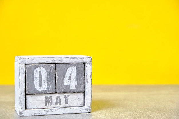 4 mei Houten bureaubladkalender gele achtergrondLentemaand afgebeeld op kubussenPlaats voor uw ideeënInternationale brandweerdag