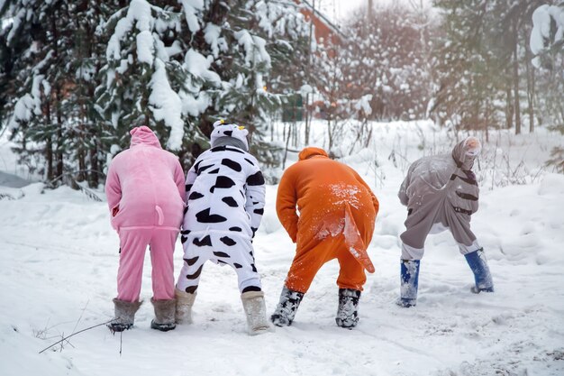 4 mensen in kigurumi in sneeuw winter bos Pyjama varken koe kangoeroe kat Plezier met wandelende vrienden