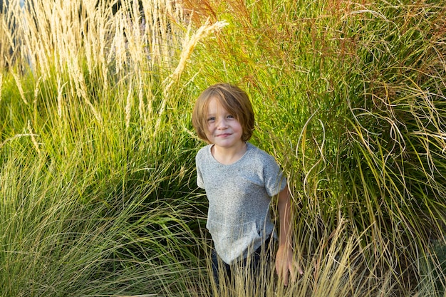 4 year old boy playing in tall grass at sunset