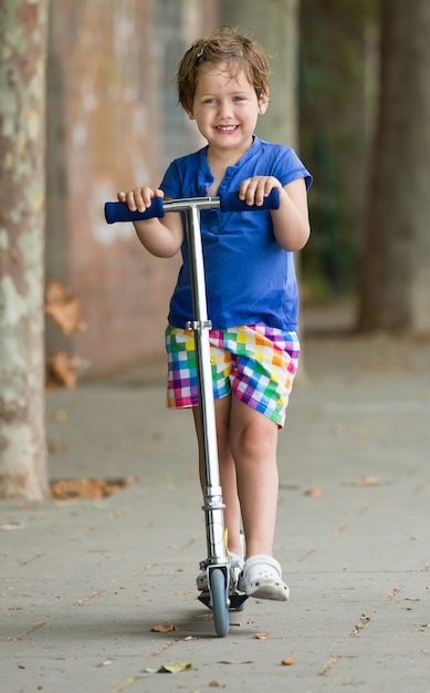 4 years old girl staying with scooter 