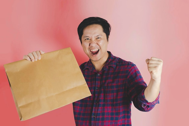 40 year old man holding brown shopping paper bag happy gesture