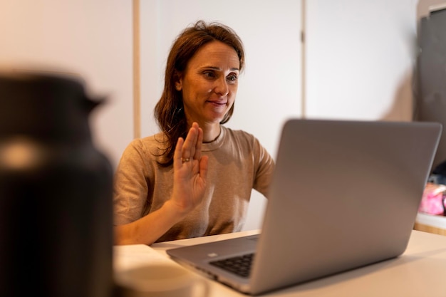 40 year old woman working at night connected to online meeting greeting for meeting with another time zone