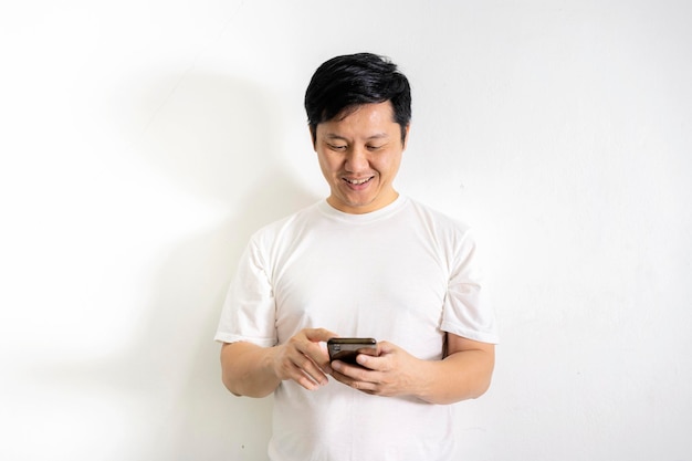 A 40yearold man wearing a white shirt is using a smartphone