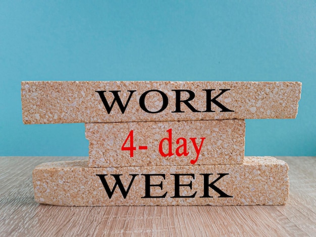 Символ 4-дневной рабочей недели Концептуальные слова «4-дневная рабочая неделя» на кирпичных блоках Красивый синий фон