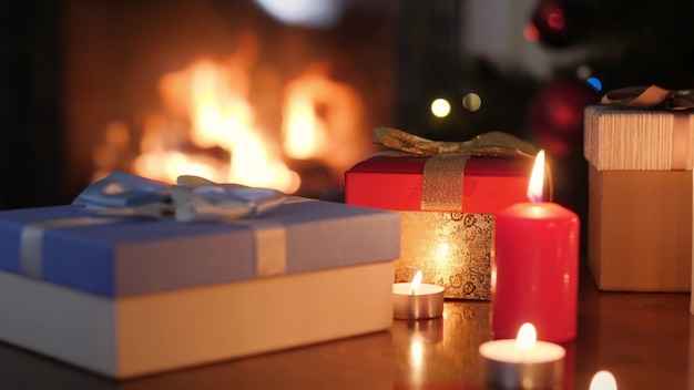 4k-beelden van dozen met kerstcadeaus en kaarsen tegen brandend vuur in firepalce in de woonkamer. Perfecte achtergrond of achtergrond voor Kerstmis of Nieuwjaar