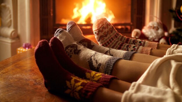 クリスマスイブに家で燃えている暖炉のそばで警告する暖かいウールの靴下を履いている家族の4k映像。冬の休日や家でのお祝いでリラックスする人々
