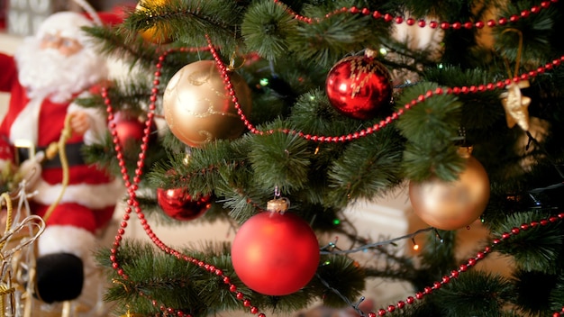 4k 패닝 영상은 거실에 있는 장식된 크리스마스 트리에 화려한 화환 구슬과 싸구려입니다. 겨울 행사와 휴가를 위한 완벽한 샷