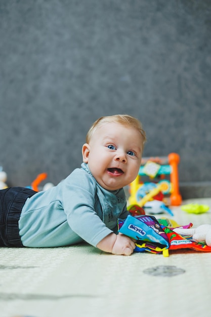A 4monthold boy lies on a mat and crawls The baby lies on a thermal mat and plays Selfdevelopment of a newborn child Toys for child development