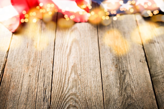 Photo 4th of july background empty wooden plank table with american usa flag and burning sparkler fireworks and golden lights bokeh happy labor independence or presidents day american flag colors