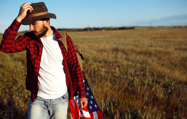 Фото 4 июля американский флаг путешественник с флагом америки человек в шляпе рюкзак рубашка