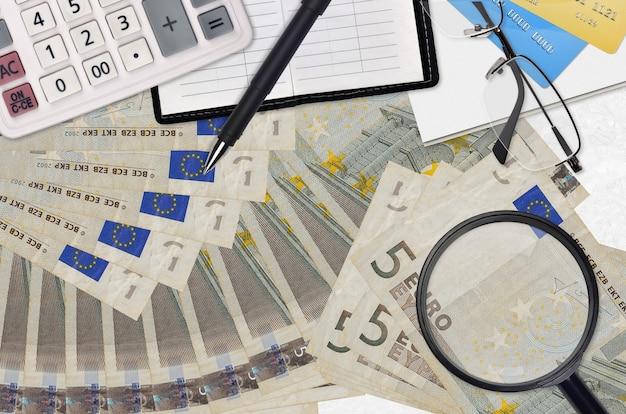 5ユーロ紙幣と電卓メガネとペン。納税シーズンのコンセプトや投資ソリューション。給与収入の多い仕事を探す