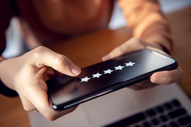 5 star rating or review in survey, poll, Customer woman hands holding smart phone Rate your experience, giving positive feedback, questionnaire or customer satisfaction research.