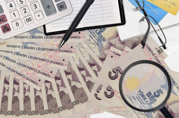 Photo 5 turkish lira bills and calculator with glasses and pen. tax payment season concept or investment solutions.