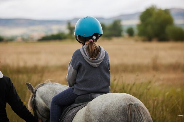 Photo 5-year-old girl riding on a horse in a hipico club infalltil sport concept