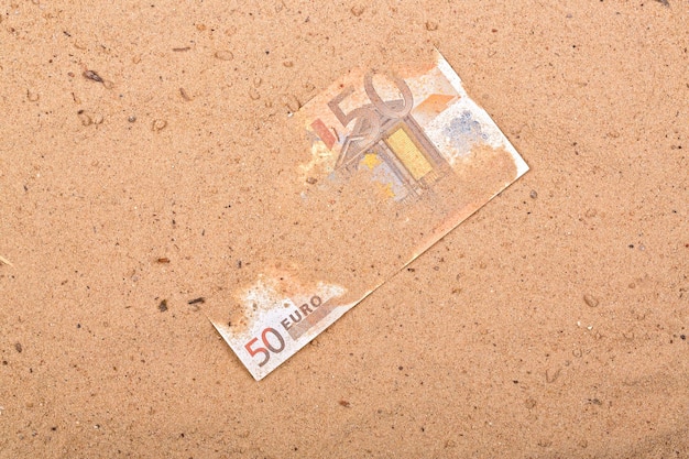 A 50 euro note is on the sand