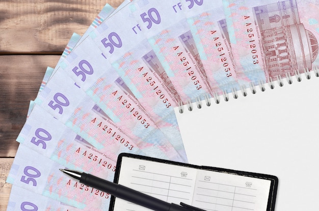 50 Ukrainian hryvnias bills fan and notepad with contact book and black pen. Concept of financial planning and business strategy