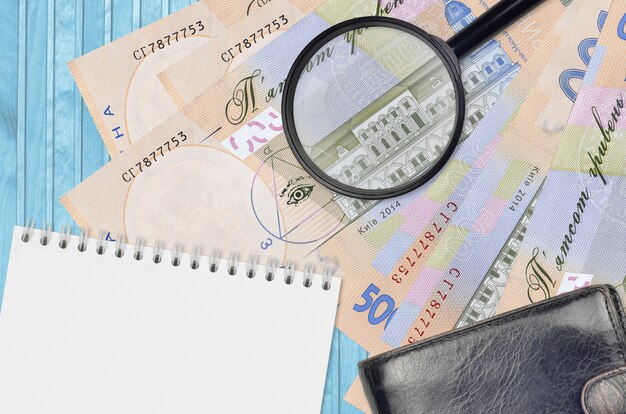 Photo 500 ukrainian hryvnias bills and magnifying glass with black purse and notepad