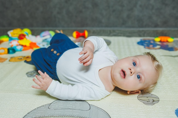 Foto un bambino di 5 mesi sorride e giace su un tappetino per lo sviluppo dello sviluppo del bambino
