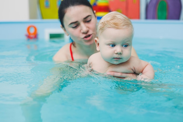 A 5monthold baby learns to swim in a pool with a coach Baby learning to swim