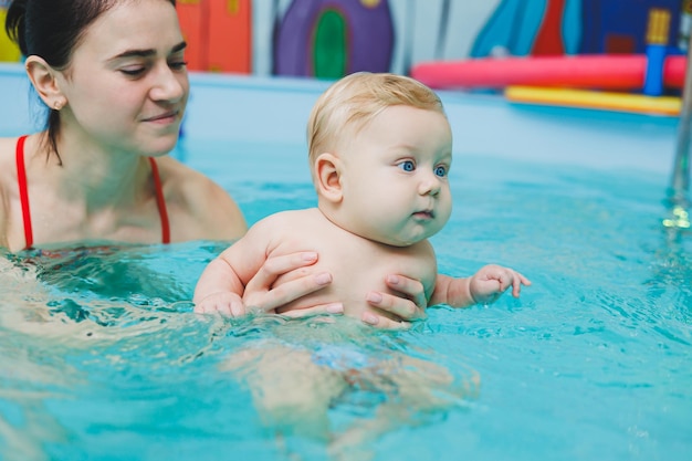 A 5monthold baby learns to swim in a pool with a coach Baby learning to swim