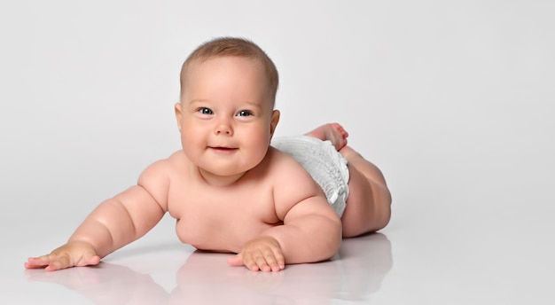 6 maanden oude baby ligt in een luier op een lichte achtergrond